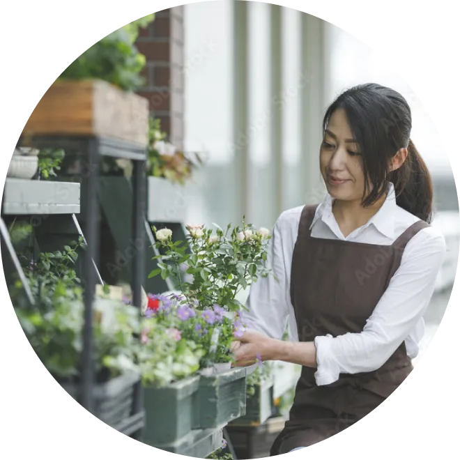 お店の店先で、鉢植えの花の手入れをする店員